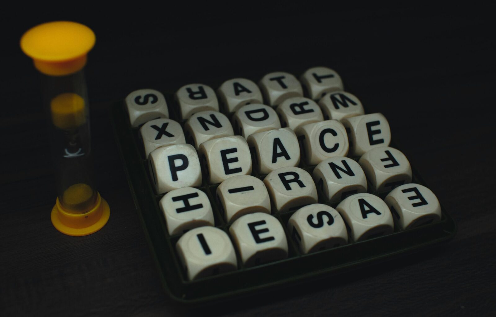 Lettered dice game with visible letters and a small timer on a dark surface.