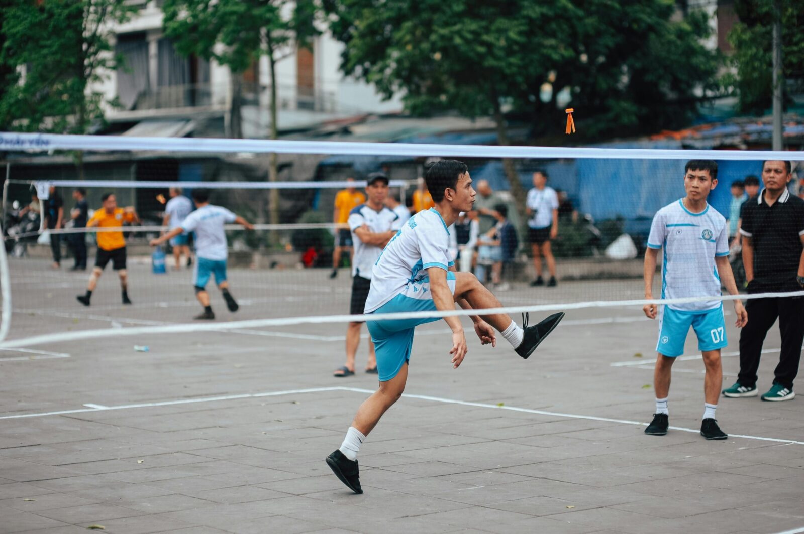 Dynamic scene of foot volleyball with young adults playing energetically outdoors.